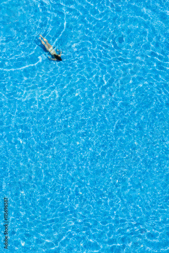 Woman swim in the pool at the hotel. Top view