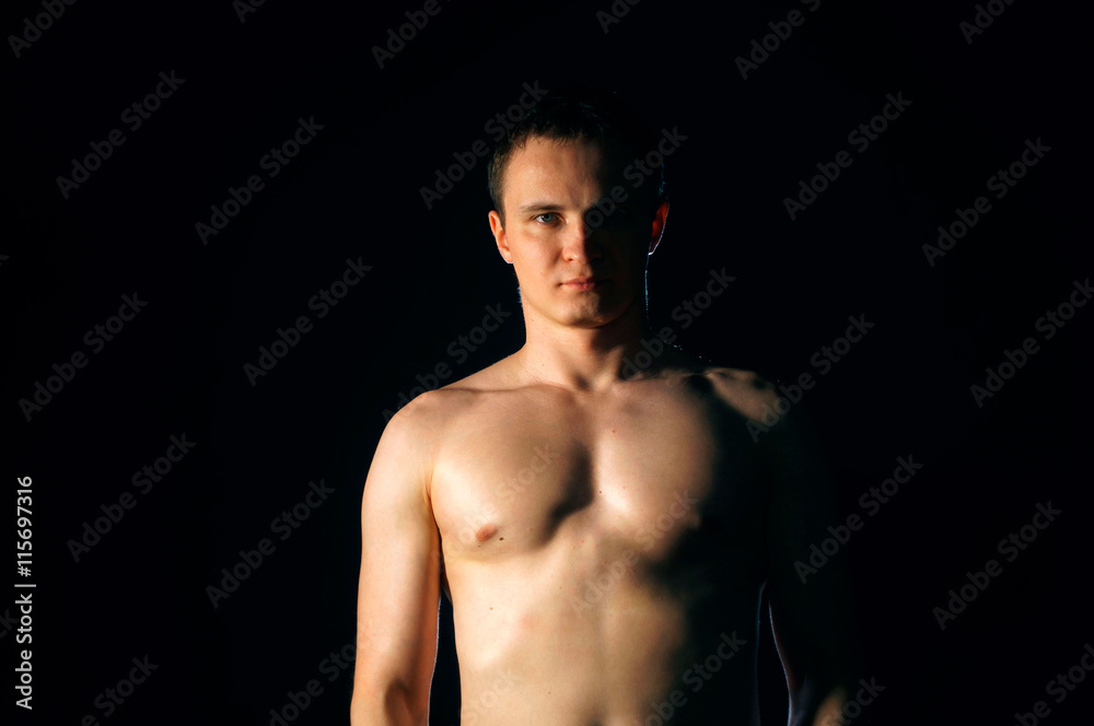 Torso of strong man against dark background Torso of strong man against dark background