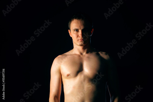 Torso of strong man against dark background