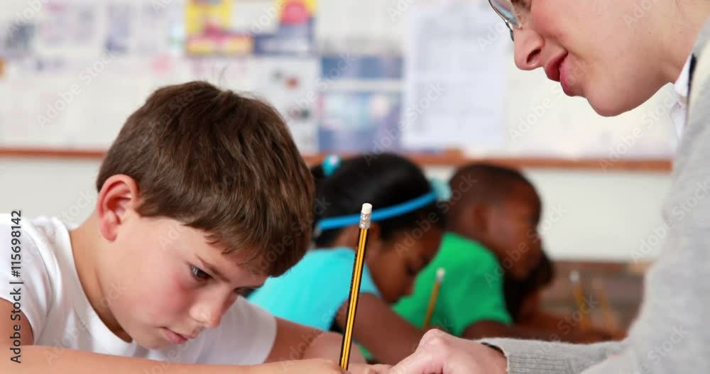 Teacher helping a little boy during class in elementary school Teacher helping a little boy during class in elementary school