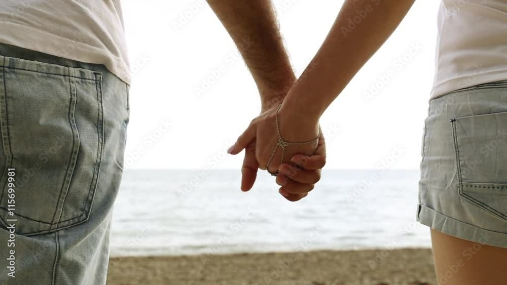 Couple holding hands on the background of the sea. Close-up of hands against the sea. Love, romance, newlyweds. Man and woman holding hands on the beach. Couple holding hands on the background of the sea. Close-up of hands against the sea. Love, romance, newlyweds. Man and woman holding hands on the beach.