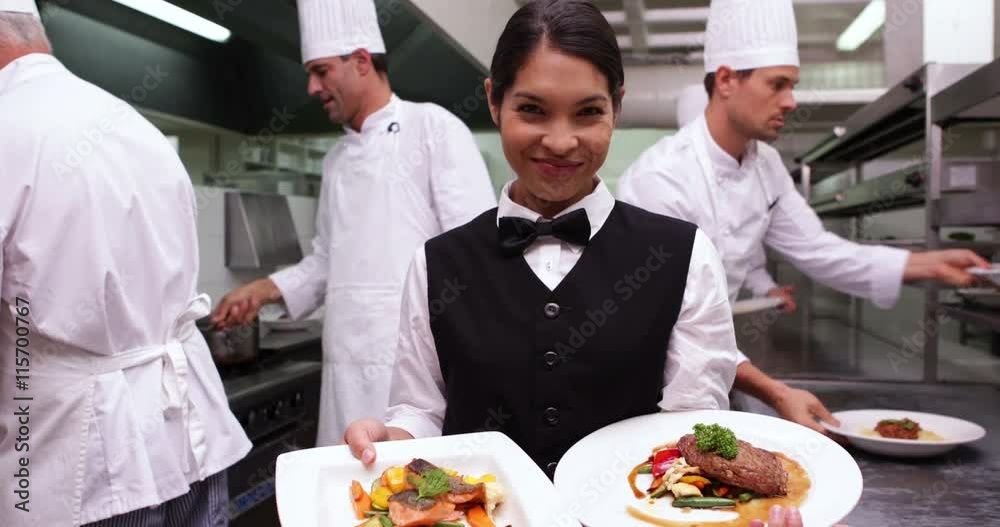 Smiling waitress showing two dishes to camera Smiling waitress showing two dishes to camera