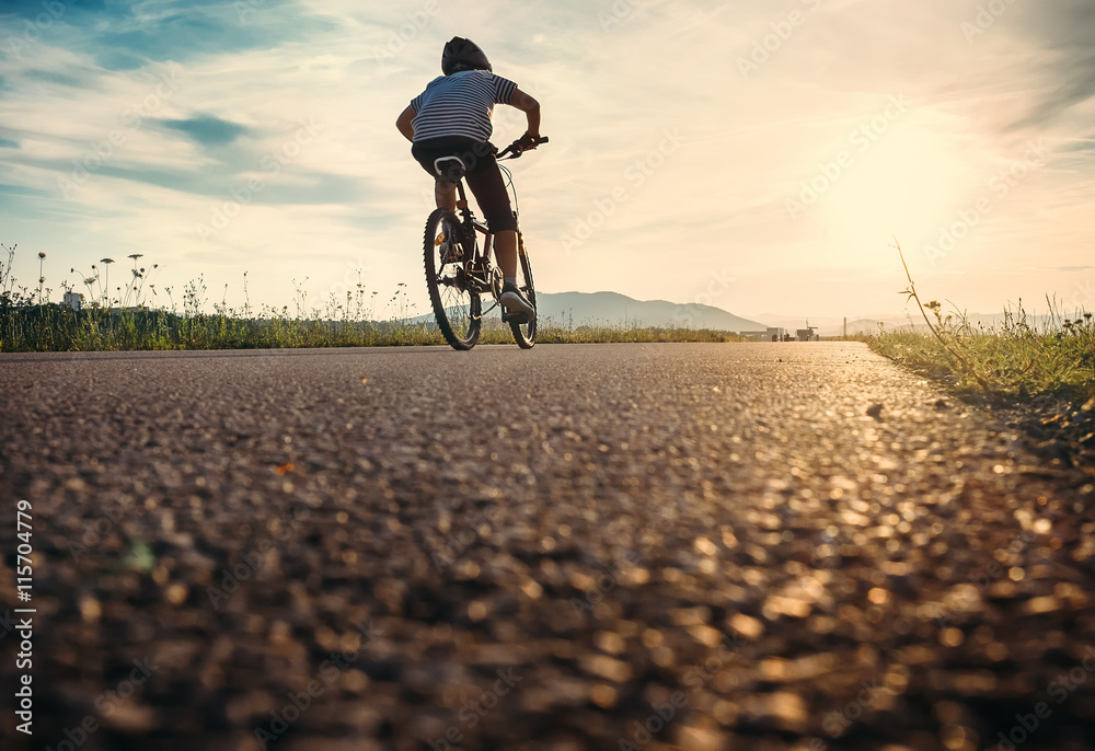 Fototapeta premium Boy rides a bicycle in the sunset light