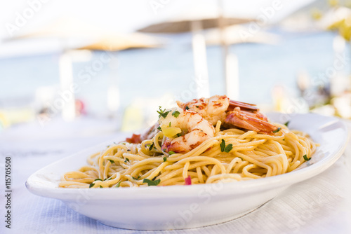 Plate of sea food, spicy pasta with shrimps served on the beach restaurant