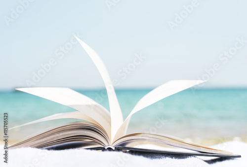 Open book on the beach towel as summertime concept