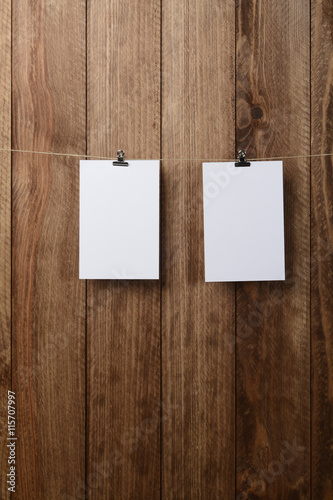 Dos tarjetas colgando de una cuerda en una pared de madera marrón