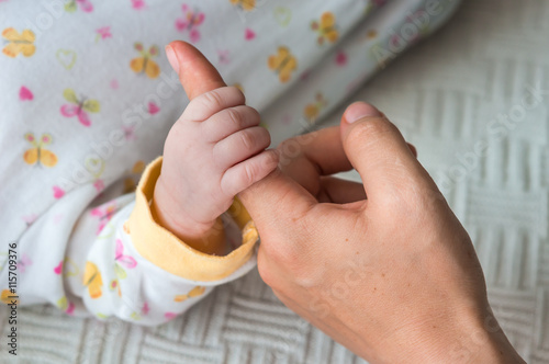 Newborns fingers touching mothers hand