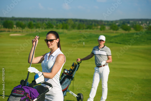 Portrait of young sportive women golfer playing golf with man at sunny day