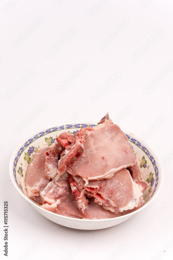 Pile of raw pork chops in the bowl over white background