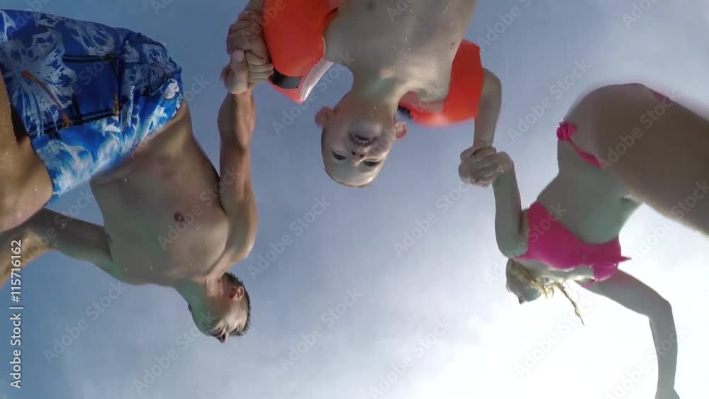 SLOW MOTION: Young parents jumping into pool with their son