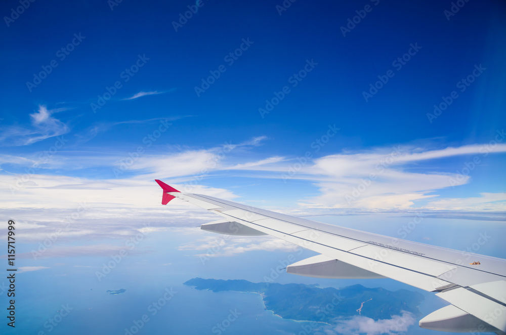 Wing of airplane flying above the clouds in the blue sky backgro Wing of airplane flying above the clouds in the blue sky backgro