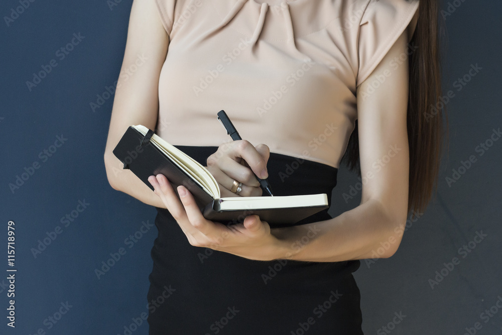 The secretary makes notes in a notebook on a blue background. Business woman The secretary makes notes in a notebook on a blue background. Business woman
