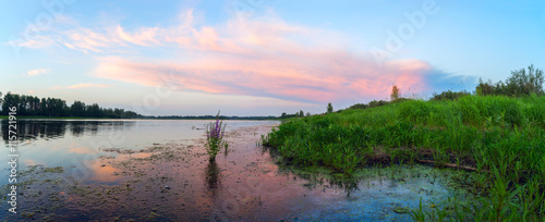Pink clouds over a lake at sunset .Panorama. © amarinchenko106