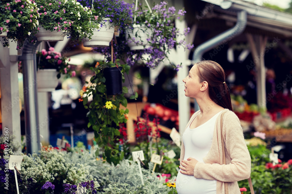 pregnant woman choosing flowers at street market