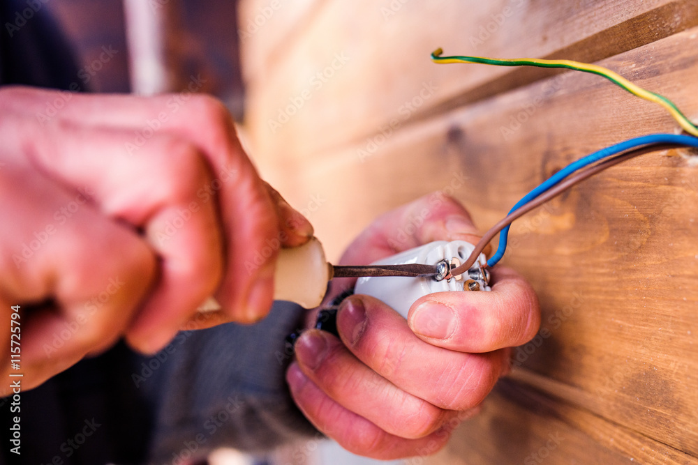 Hands of unrecognizable electrician working with screwdriver Hands of unrecognizable electrician working with screwdriver