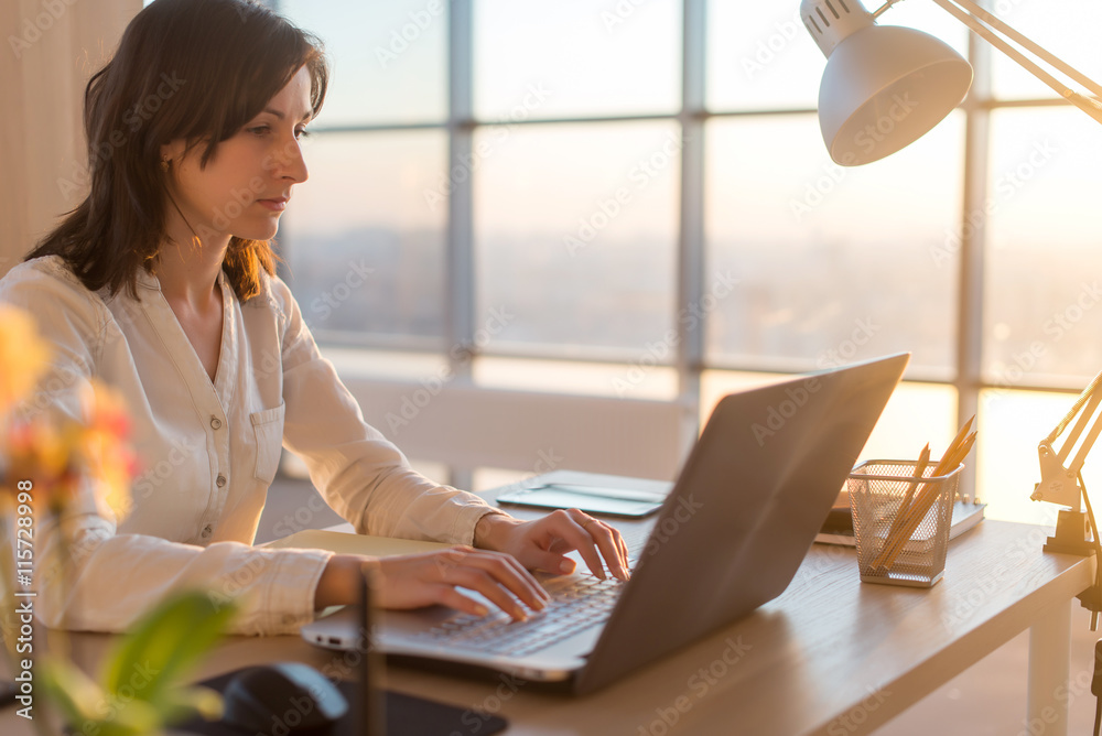 Side view photo of a female programmer using laptop, working, typing, surfing the internet at workplace. Side view photo of a female programmer using laptop, working, typing, surfing the internet at workplace.