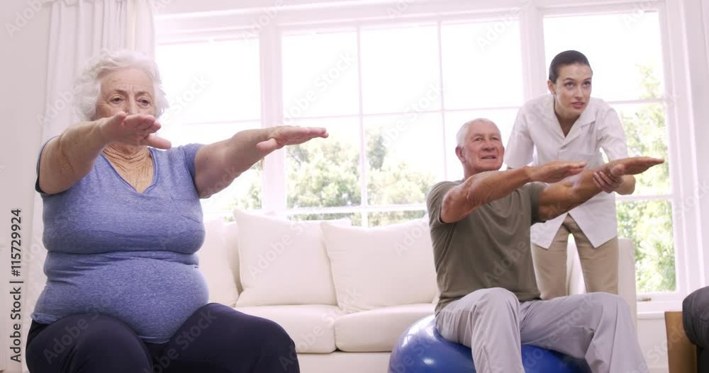 Smiling nurse helping senior couple doing exercises Smiling nurse helping senior couple doing exercises