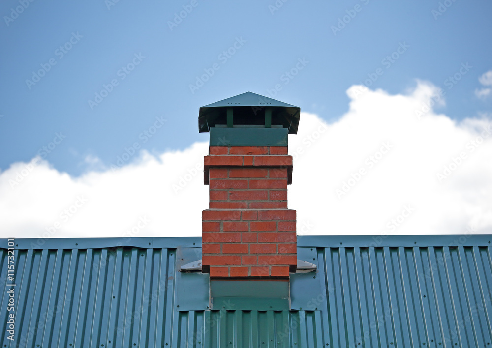 Brick chimney on the green metal roof