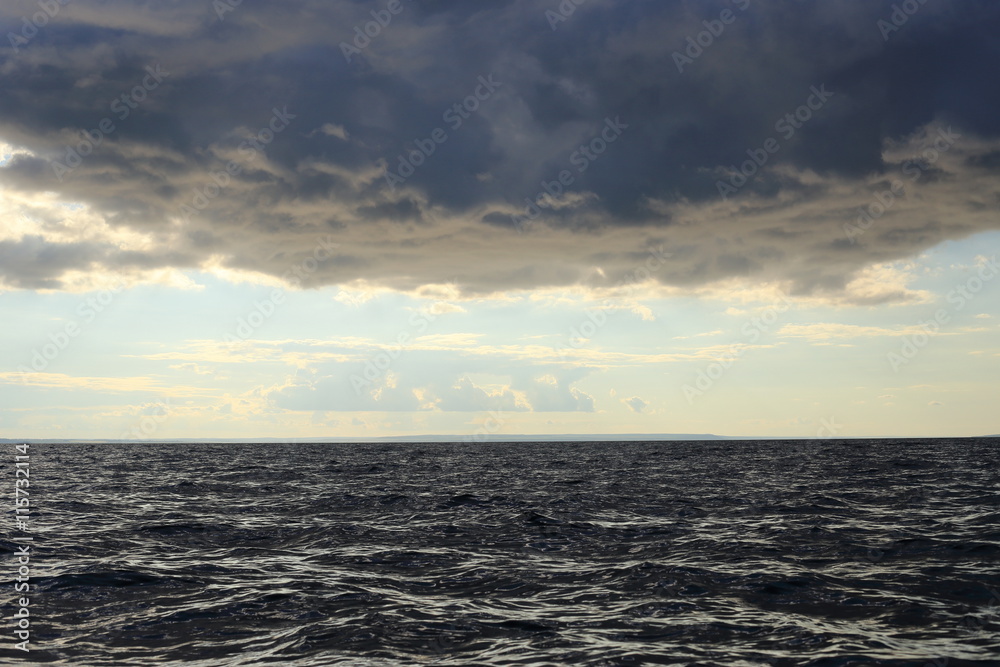 
at the bottom of the dark water, dark clouds at the top, in the middle of the bright horizon
