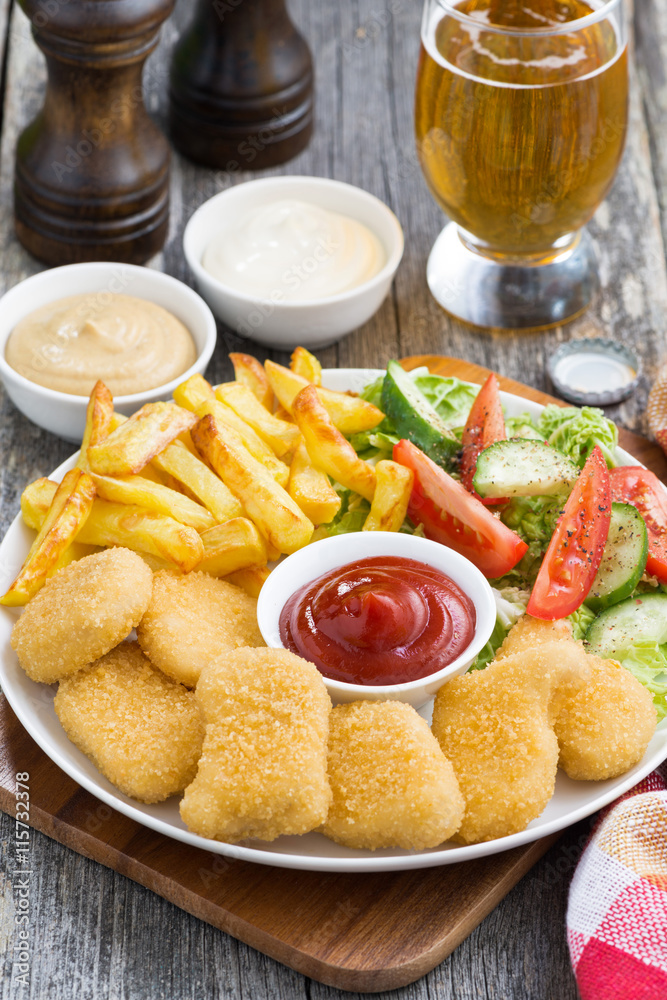 lunch with chicken nuggets, french fries, salad and beer