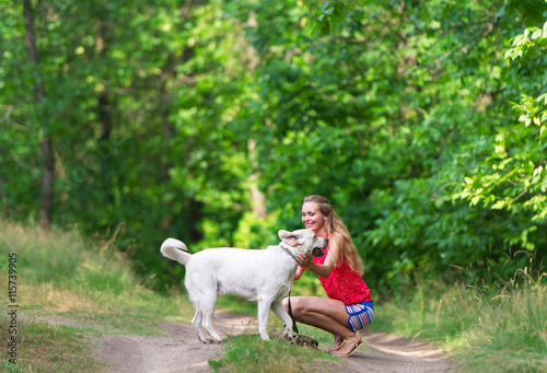 The beautiful girl and dog have sat down on a forest footpath