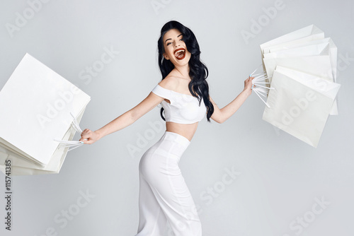 Shopping woman holding bags, isolated on gray studio background.