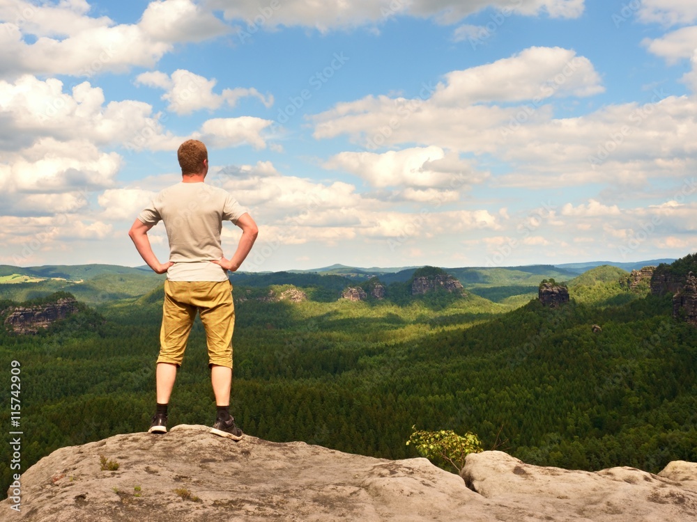 Man in trekking shorts on cliff of rock empire watch Man in trekking shorts on cliff of rock empire watch
