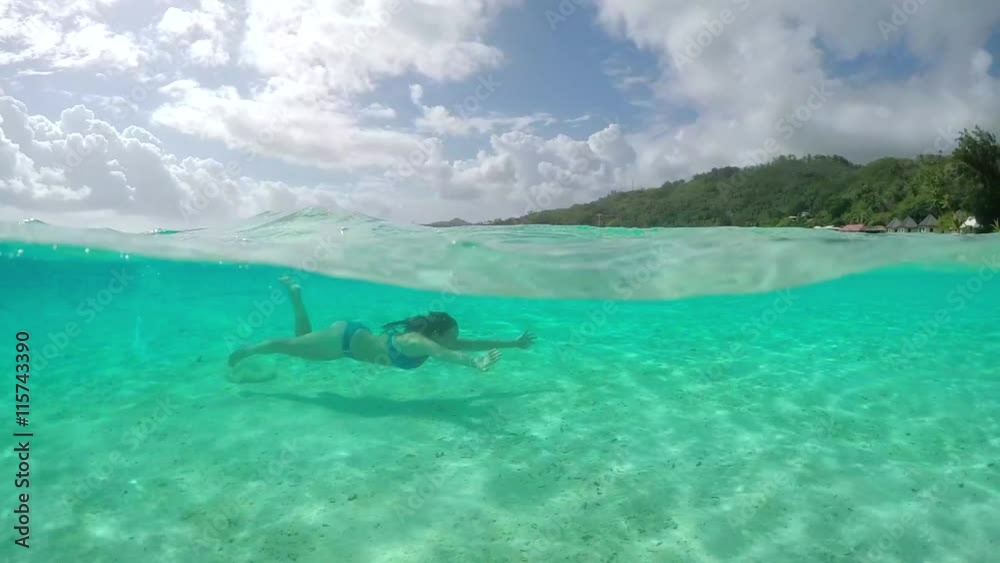 SLOW MOTION: Young woman swimming underwater in perfect blue lagoon SLOW MOTION: Young woman swimming underwater in perfect blue lagoon