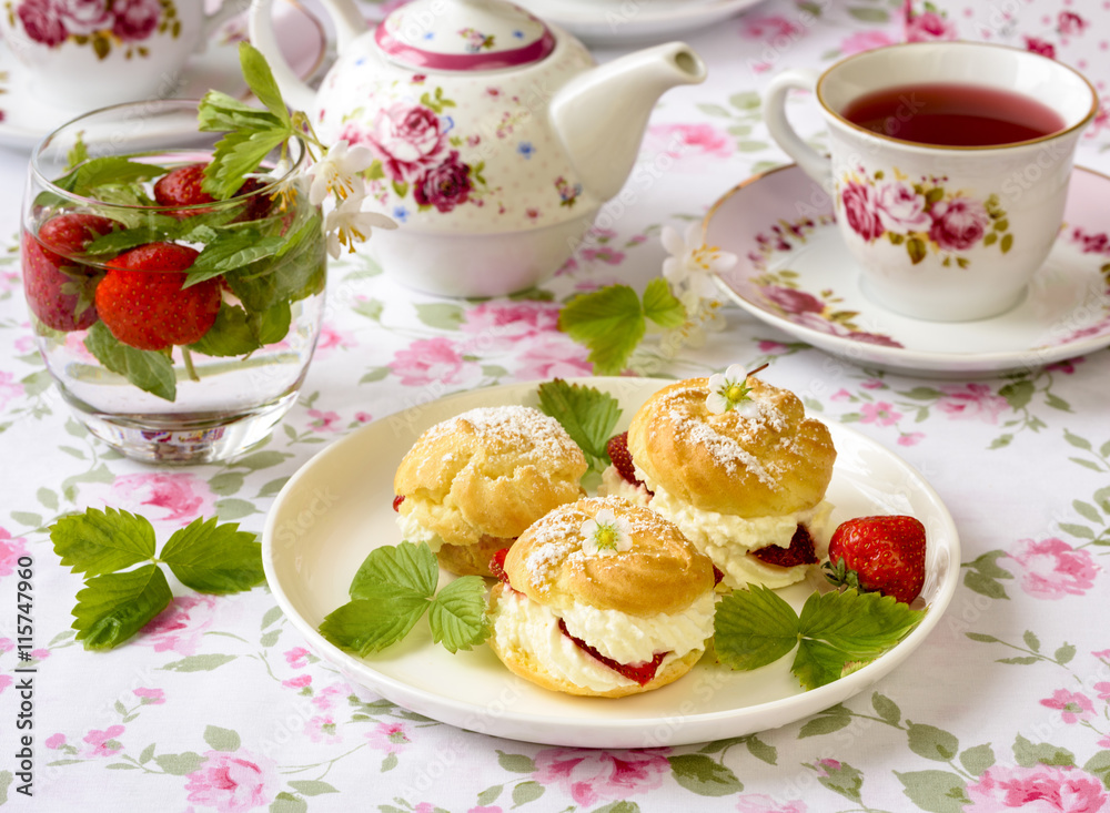 Cream puff cakes or profiterole filled with whipped cream, served with strawberries Cream puff cakes or profiterole filled with whipped cream, served with strawberries