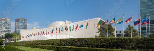 UN United Nations general assembly building with world flags fly - 3:1 aspect ratio