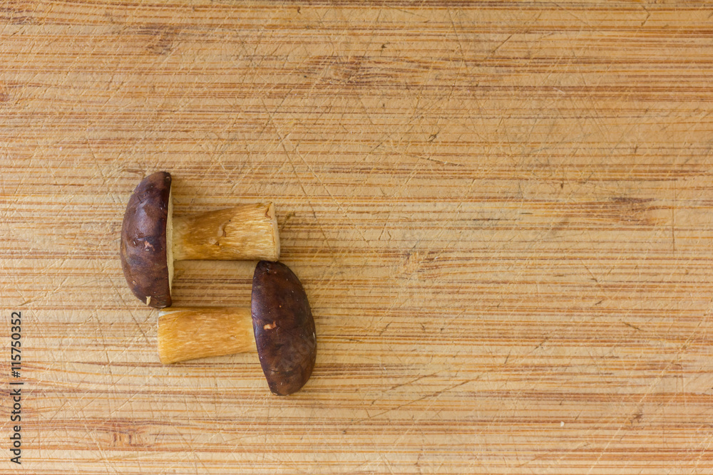 ein Pilz liegt in zwei Teile geschnitten auf einem Holzbrett