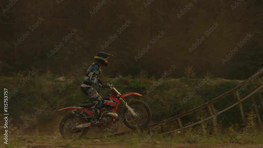 SLOW MOTION CLOSE UP: Extreme motocross biker jumping over the sun SLOW MOTION CLOSE UP: Extreme motocross biker jumping over the sun