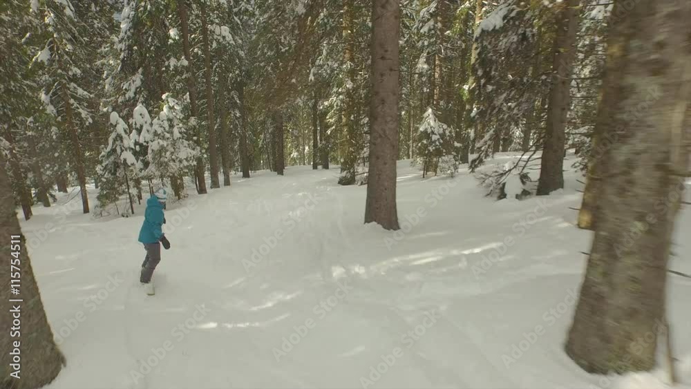 AERIAL: Female snowboarder riding through the forest AERIAL: Female snowboarder riding through the forest