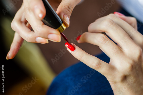 Woman with long fingers and nails applying transparent nail base at home  close up photo