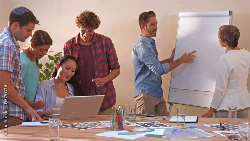 Creative business team working on laptop while their colleagues looking at white board Creative business team working on laptop while their colleagues looking at white board
