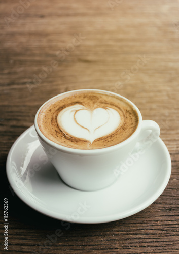 Cup of Cappuccino Coffee with Heart shape Latte Art on wood back