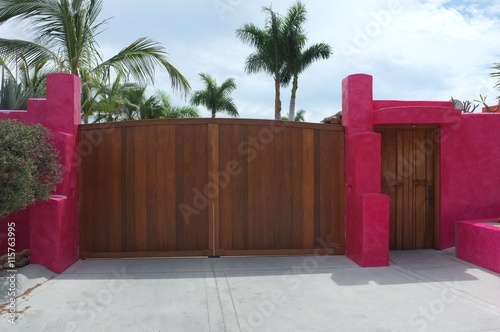 Wooden gate and door on bright pink wall