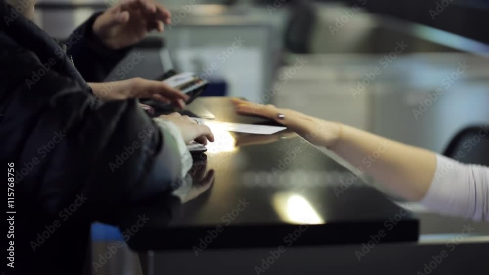 The receptionist sitting in airport reception area is working with clients giving passport or identity card back