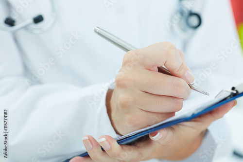 Female medicine doctor hand holding silver pen writing something on clipboard closeup. Ward round, patient visit check, medical calculation and statistics concept. Physician ready to examine patient