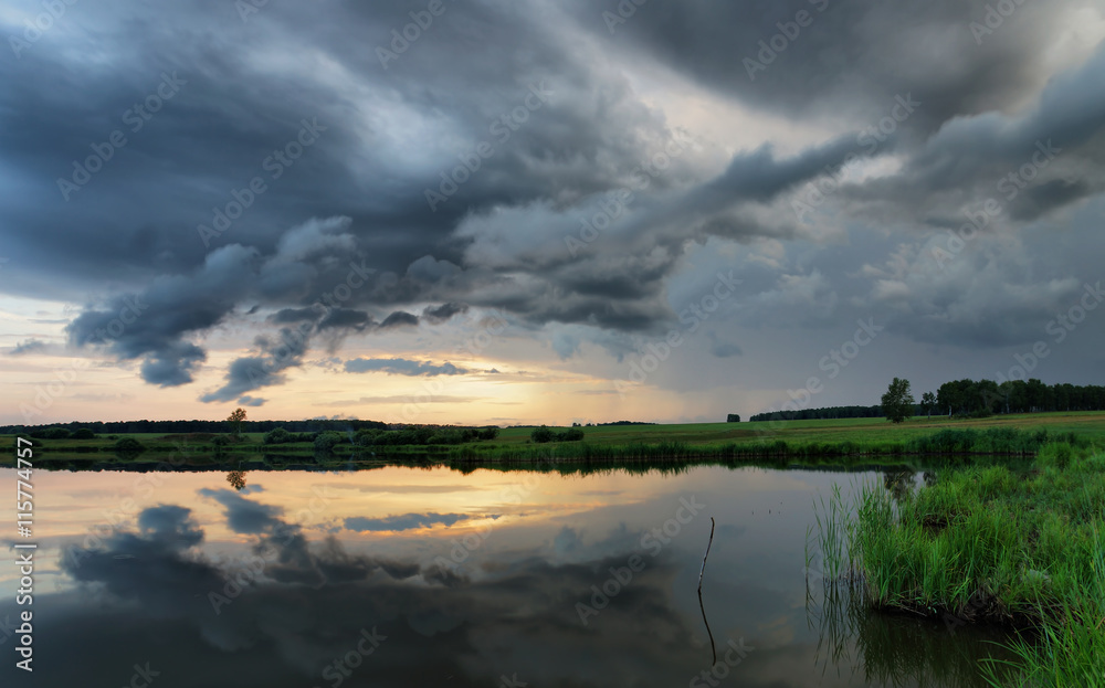 Fototapeta premium Dramatic summer sunset at the lake with dark clouds before storm