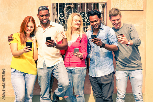 Row of multiracial happy friends holding phone hanging to urban wall - Cheerful teens lined up addicted to internet social network - Concept of modern trend head down on smartphone and social changes