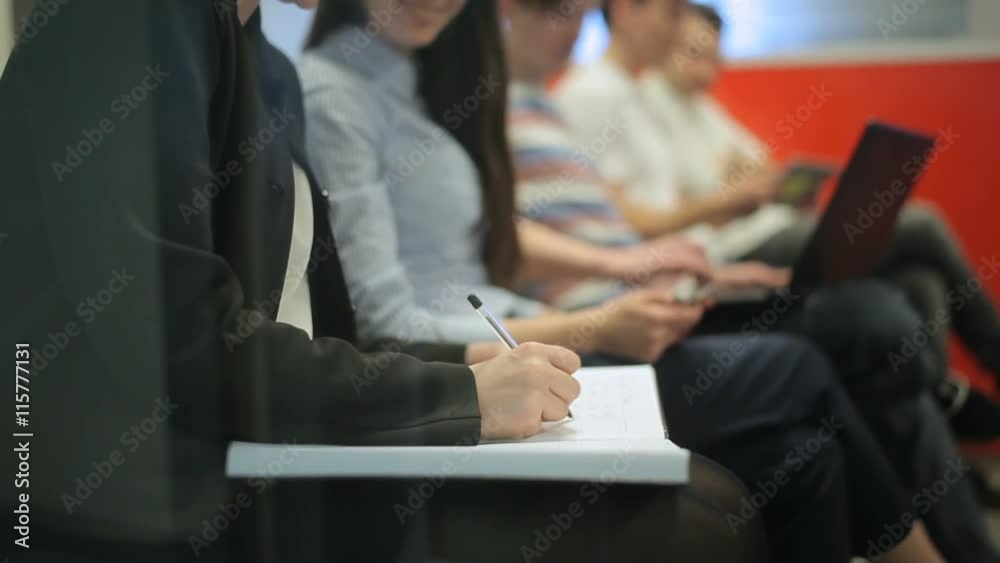 A girl talking with girl and writting notes in the office A girl talking with girl and writting notes in the office