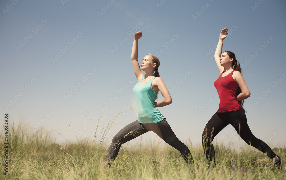 Young two women doing yoga outdoors photo stay and shows poses Young two women doing yoga outdoors photo stay and shows poses