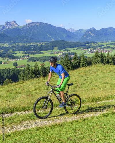 Mountainbiker radlet auf einem Bergrücken mit toller Aussicht im Allgäu
