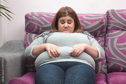 Woman touching her belly fat on the couch