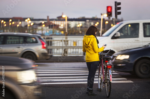 Full length of woman using smart phone while standing with bicycle on city street