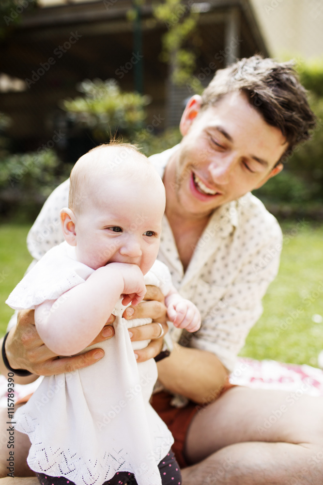 Happy mid adult man looking at baby girl in yard Happy mid adult man looking at baby girl in yard