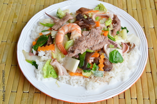 stir fried mixed vegetable with seafood and pork on rice