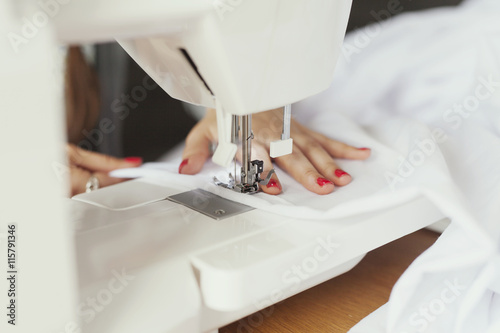 Cropped hands of fashion designer using sewing machine photo