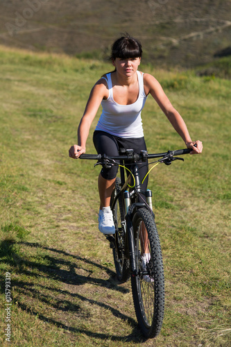 Fototapeta Naklejka Na Ścianę i Meble -  Young lady with bicycle on a spring meadow